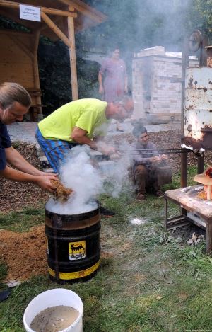 Ak.soch. Hluštík (v popředí) vhazuje piliny do sudu, kde probíhá měděné zabarvení glazury